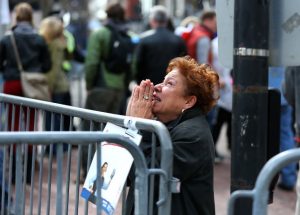 A woman kneels and prays at the scene of the first explosion on Boylston Street near the finish line of the 117th Boston Marathon on April 15, 2013. (Photo by John Tlumacki/The Boston Globe via Getty Images)